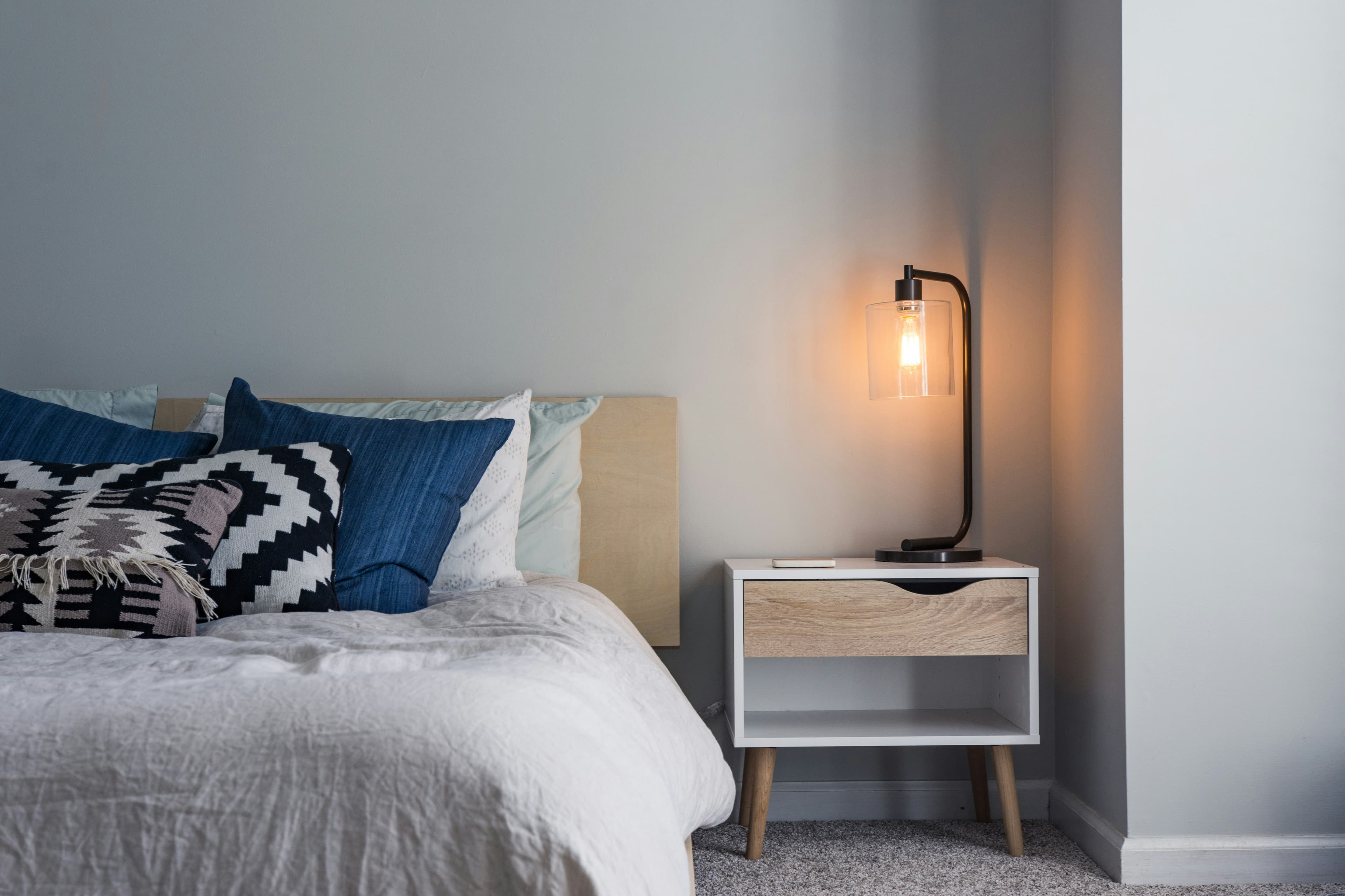 Freshly made bed with clean linen and a bedside lamp