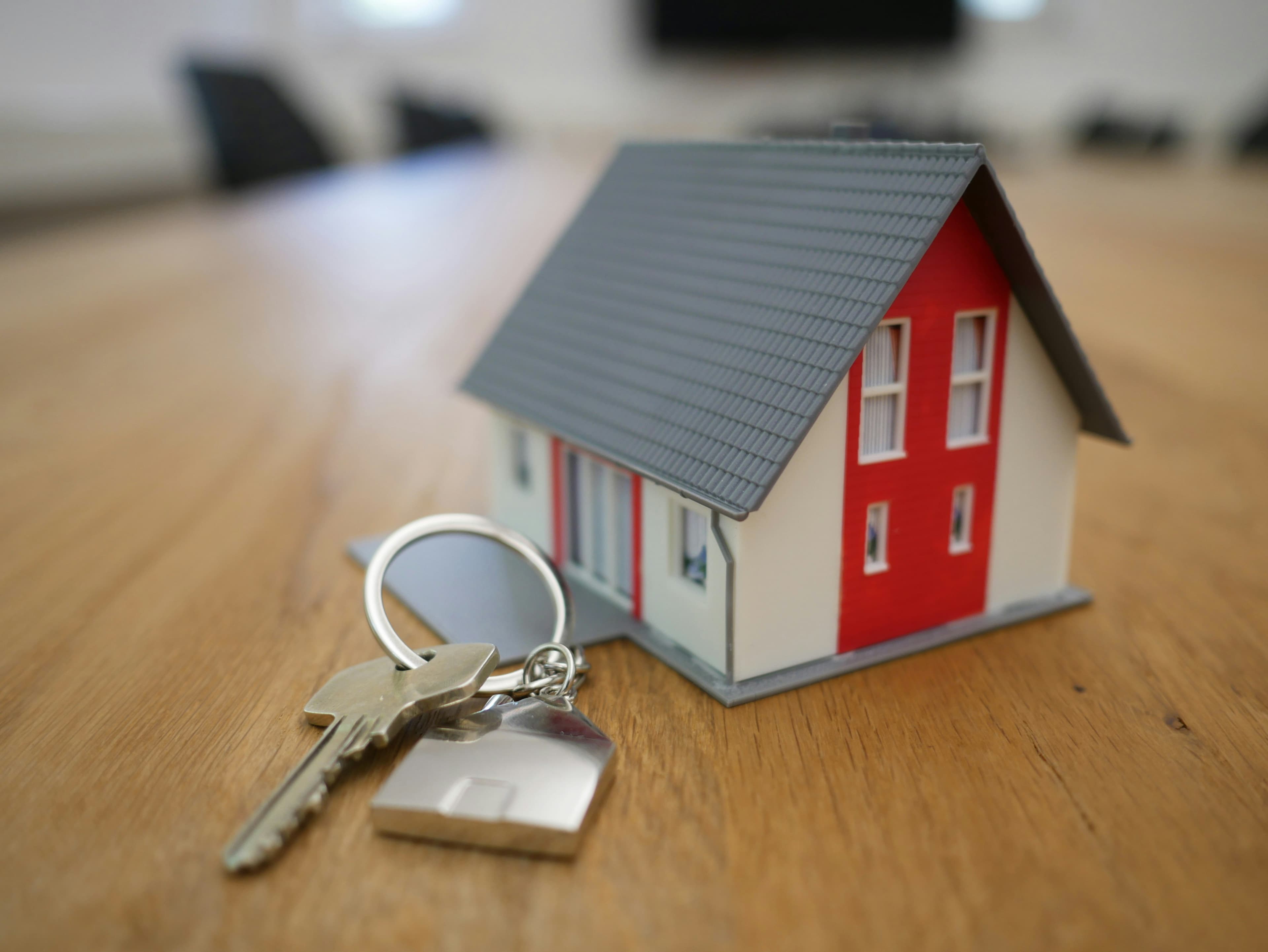 House keys resting beside a small model house on a table