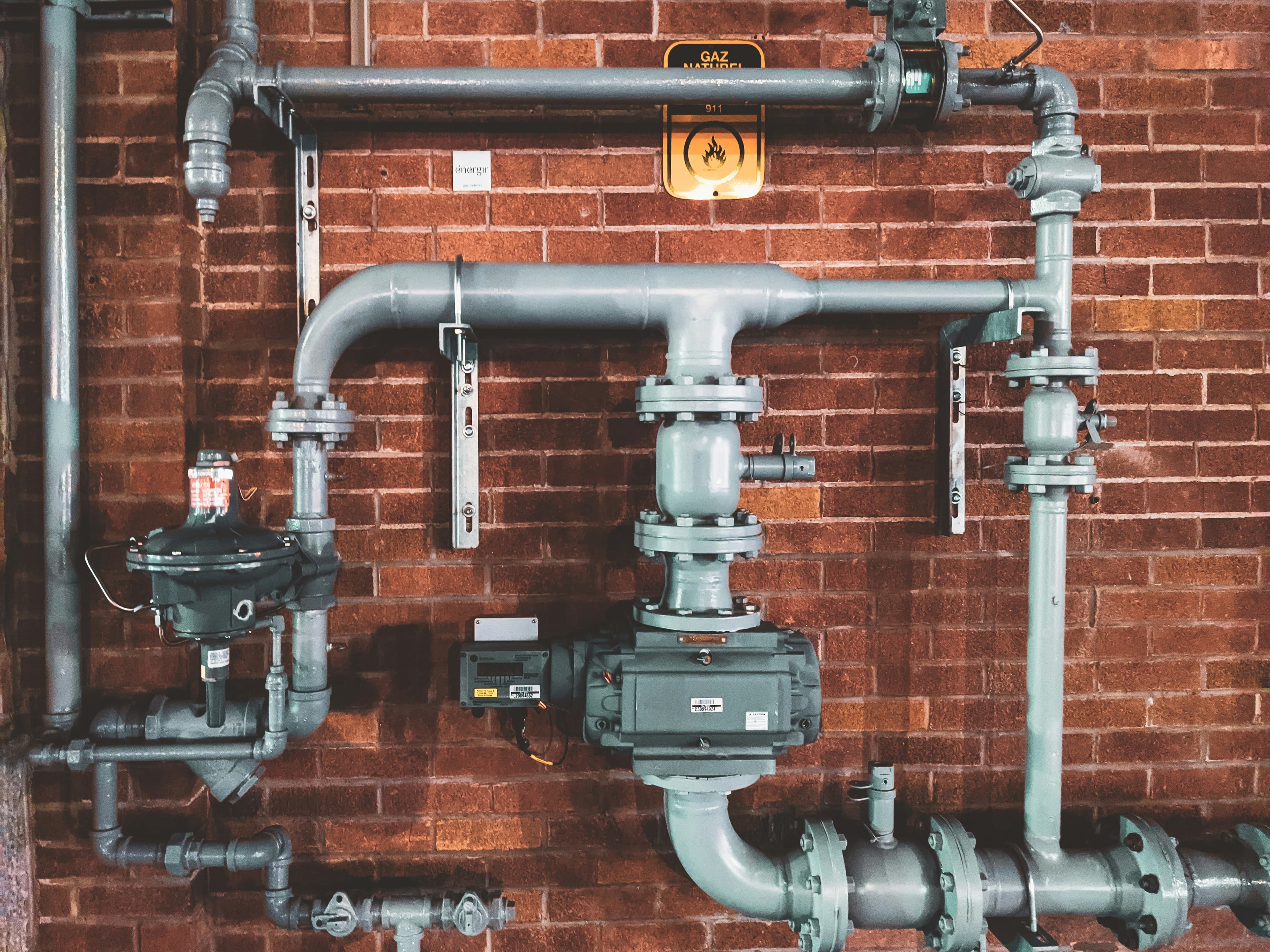 Serviced heating pipework and valves against a brick wall